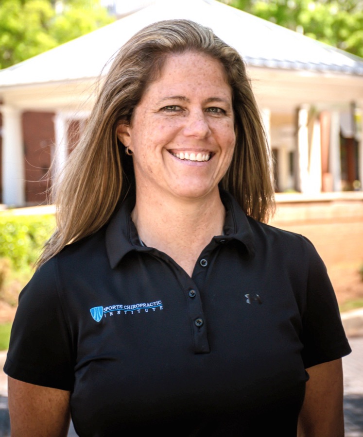 Portrait of Dr. Ashli Linkhorn smiling outdoors in a black polo shirt
